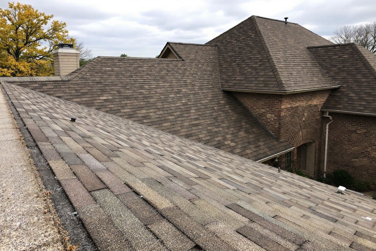 Intersecting shingle roof planes above a red brick home